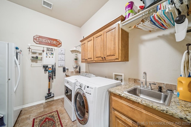 washroom with visible vents, cabinet space, a sink, baseboards, and washer and dryer