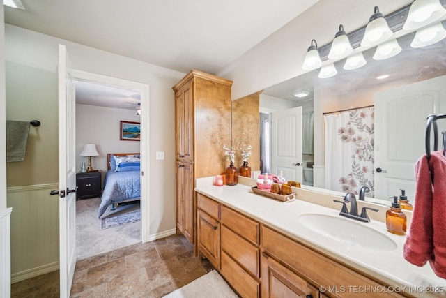 full bath featuring stone finish floor, curtained shower, vanity, baseboards, and connected bathroom