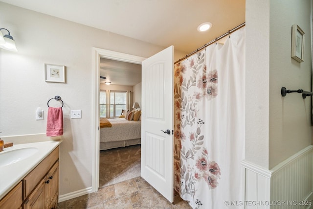 ensuite bathroom featuring a shower with shower curtain, ensuite bath, stone finish floor, and vanity
