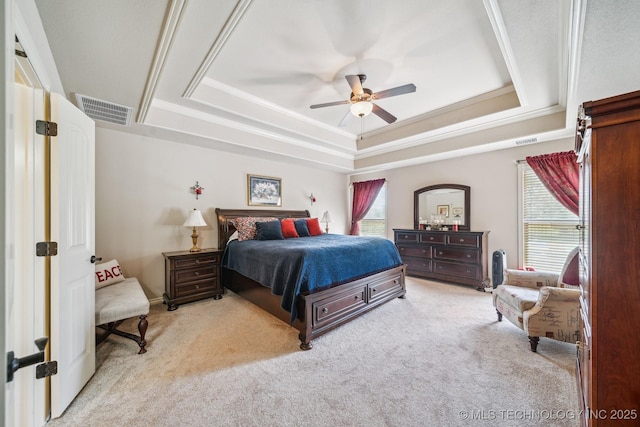 bedroom with multiple windows, a tray ceiling, carpet flooring, and visible vents
