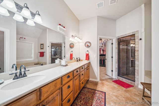 full bath with visible vents, a sink, double vanity, and a shower stall