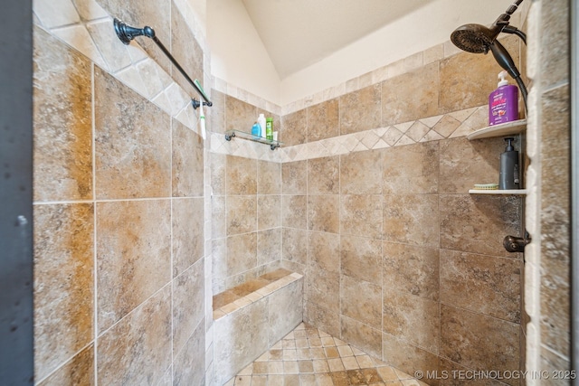 bathroom featuring a tile shower and lofted ceiling