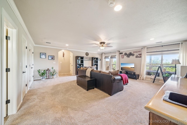living room with crown molding, arched walkways, light carpet, and a ceiling fan