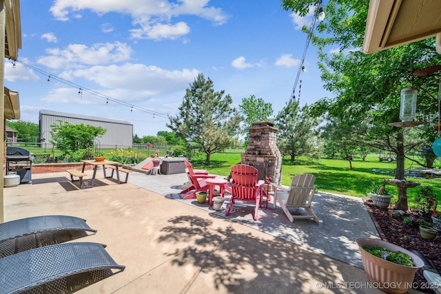 view of patio / terrace featuring an outdoor stone fireplace, fence, and a grill