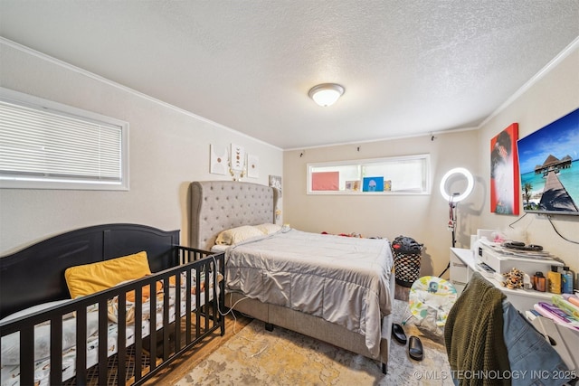 bedroom with crown molding, a textured ceiling, and wood finished floors