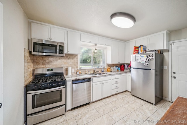 kitchen featuring white cabinets, stainless steel appliances, decorative backsplash, and a sink