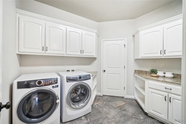 washroom with washing machine and clothes dryer, baseboards, stone finish flooring, and cabinet space