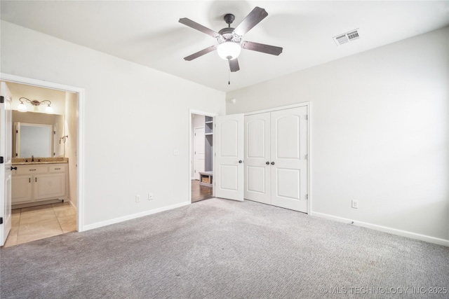 unfurnished bedroom with visible vents, light carpet, baseboards, ensuite bathroom, and a sink