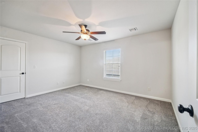 carpeted spare room featuring baseboards, visible vents, and ceiling fan
