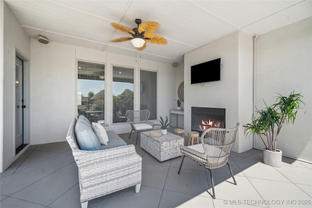 view of patio / terrace with ceiling fan and an outdoor living space with a fireplace