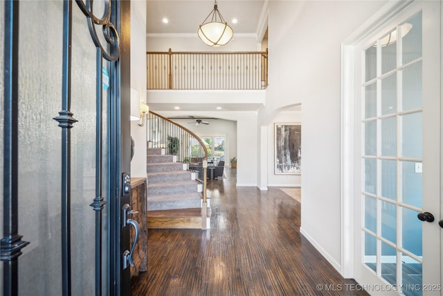 foyer entrance featuring dark wood-style flooring, a high ceiling, stairs, a ceiling fan, and baseboards