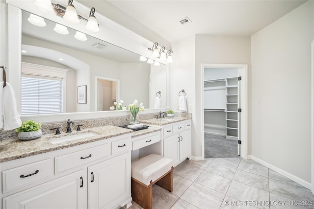 bathroom with double vanity, visible vents, a sink, baseboards, and marble finish floor