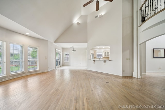 8655 E 103rd St, Tulsa, OK 74133 - unfurnished living room featuring a ceiling fan, high vaulted ceiling, light wood-style floors, baseboards, and a chandelier
