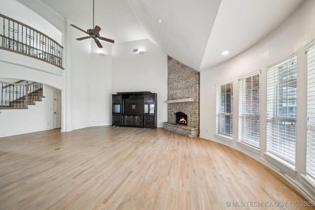 8655 E 103rd St, Tulsa, OK 74133 - unfurnished living room featuring a stone fireplace, healthy amount of natural light, high vaulted ceiling, a ceiling fan, and wood finished floors
