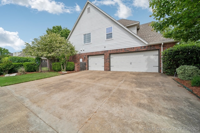 8655 E 103rd St, Tulsa, OK 74133 - view of home's exterior featuring brick siding, concrete driveway, a garage, and a shingled roof