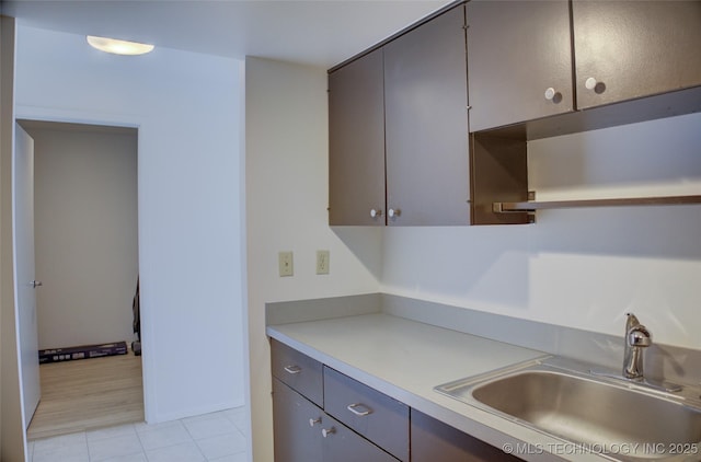 kitchen featuring gray cabinets, open shelves, a sink, light tile patterned floors, and light countertops