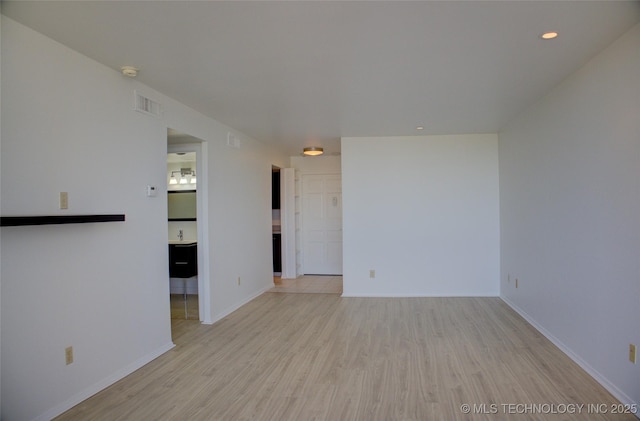 unfurnished room with baseboards, visible vents, and wood finished floors