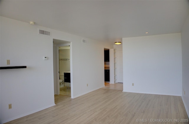 unfurnished room featuring baseboards, visible vents, and light wood-type flooring