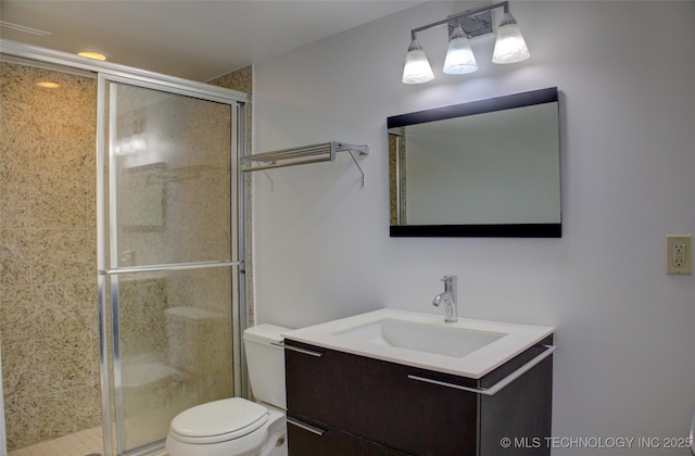 full bathroom featuring vanity, a stall shower, and toilet