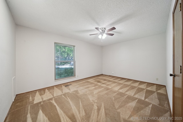 spare room featuring a ceiling fan, carpet flooring, a textured ceiling, and visible vents