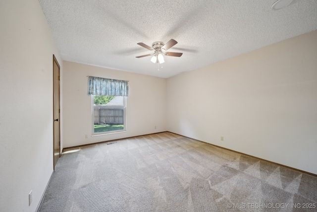 unfurnished room with a ceiling fan, a textured ceiling, visible vents, light colored carpet, and baseboards