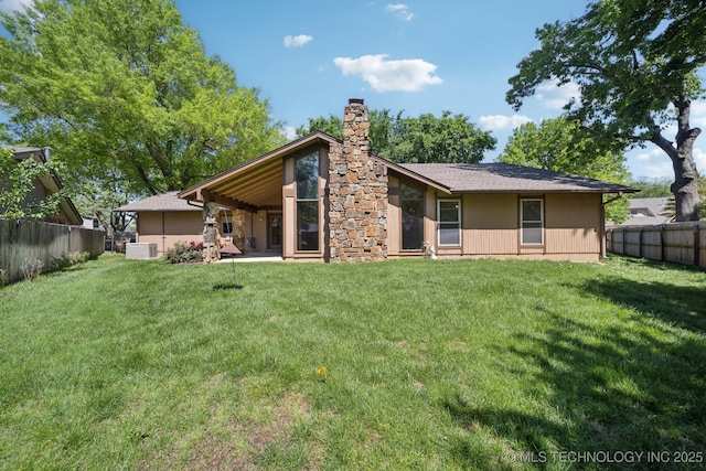 back of house with a lawn, a fenced backyard, and a chimney