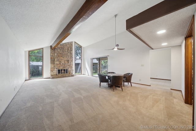 dining space with ceiling fan, a stone fireplace, a textured ceiling, and light colored carpet