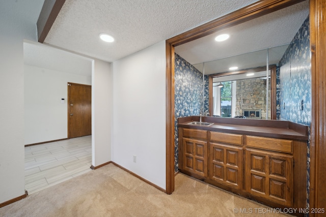 bathroom featuring baseboards, a textured ceiling, a stone fireplace, and vanity