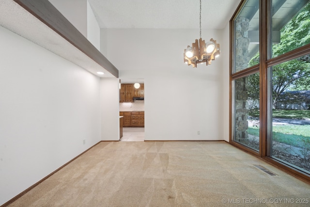 unfurnished dining area with visible vents, baseboards, a chandelier, and light carpet