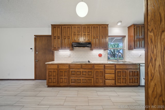 kitchen with brown cabinets, a sink, backsplash, under cabinet range hood, and stainless steel dishwasher