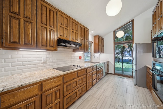 kitchen featuring brown cabinetry, decorative backsplash, under cabinet range hood, and black appliances