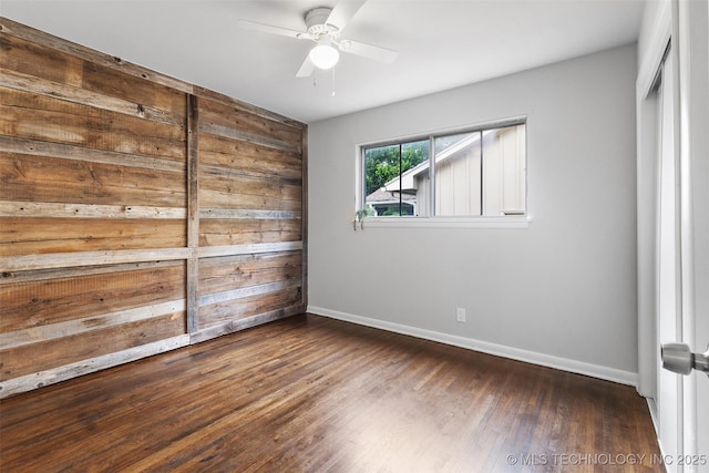 spare room with dark wood-style flooring, baseboards, and ceiling fan