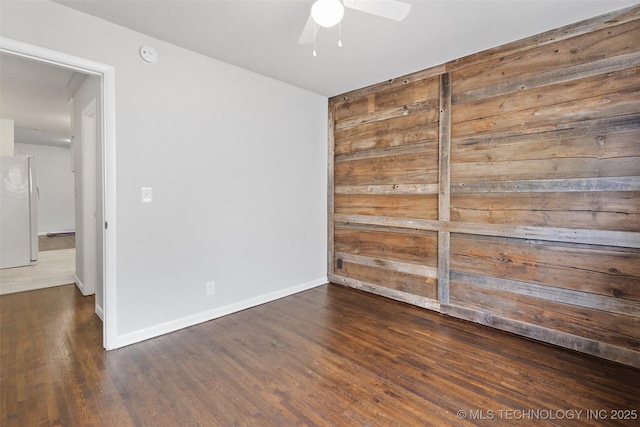unfurnished room with baseboards, a ceiling fan, and wood finished floors