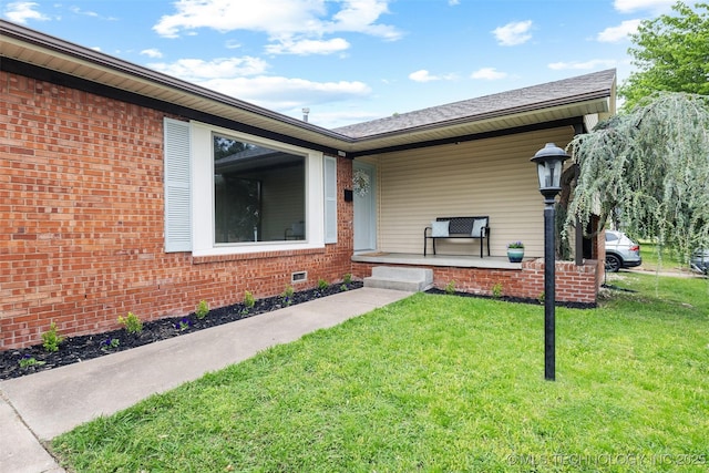 property entrance with a lawn, brick siding, and covered porch