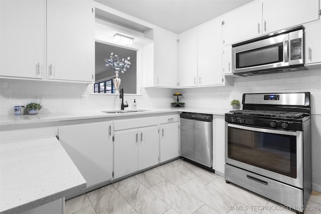 kitchen with a sink, tasteful backsplash, white cabinets, and stainless steel appliances