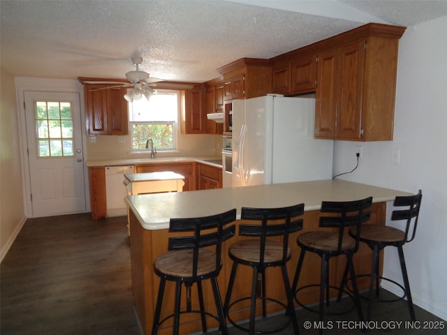 177 Lakeaire Dr, Eufaula, OK 74432 - kitchen with white appliances, light countertops, a peninsula, a ceiling fan, and dark wood-style floors