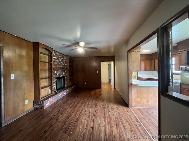12131 E 31st Pl, Tulsa, OK 74146 - unfurnished living room with wood finished floors, ceiling fan, a fireplace, and built in shelves