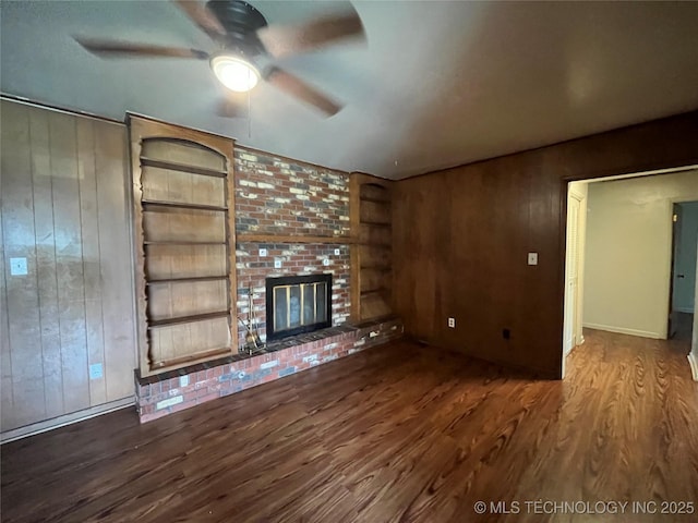 12131 E 31st Pl, Tulsa, OK 74146 - unfurnished living room with wood finished floors, wooden walls, ceiling fan, a fireplace, and built in features