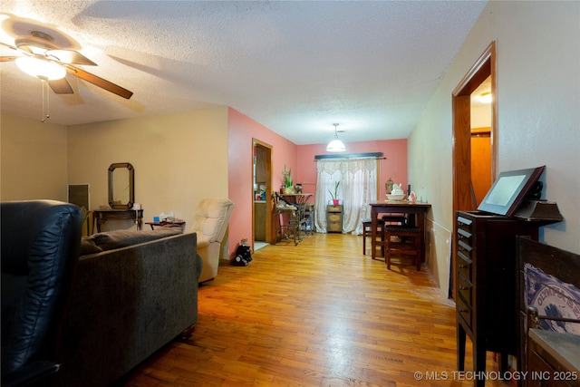 living area with a ceiling fan and wood finished floors