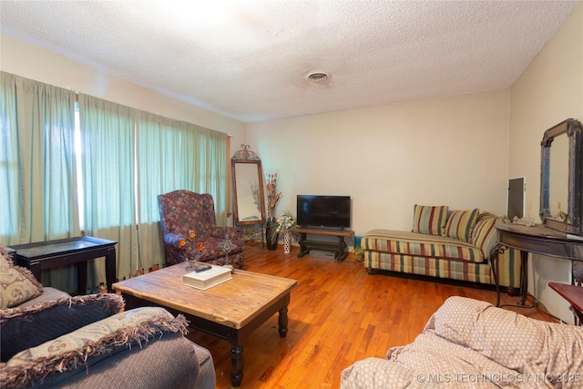 living room with visible vents, a textured ceiling, and wood finished floors