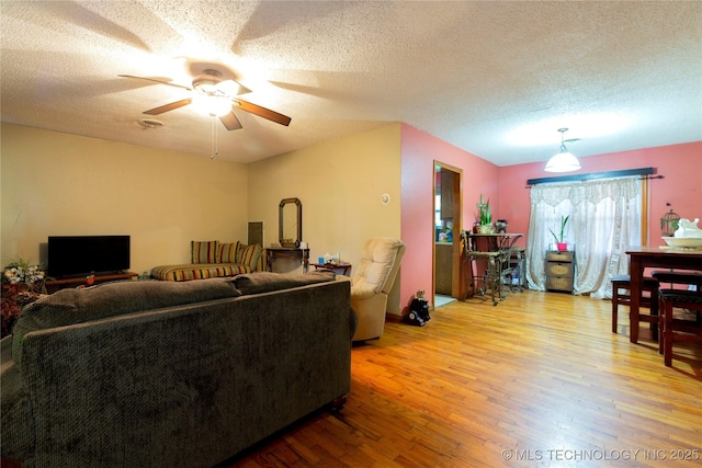 living room featuring a textured ceiling, ceiling fan, and wood finished floors