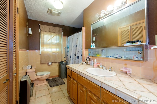 bathroom featuring visible vents, vanity, toilet, tile walls, and tile patterned floors