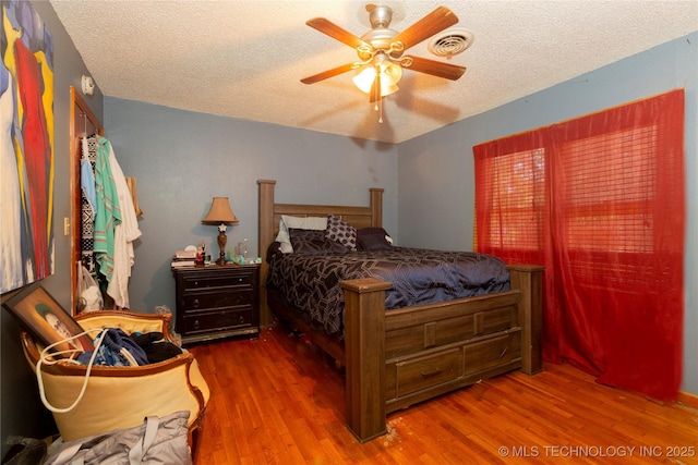 bedroom featuring visible vents, a textured ceiling, and wood finished floors