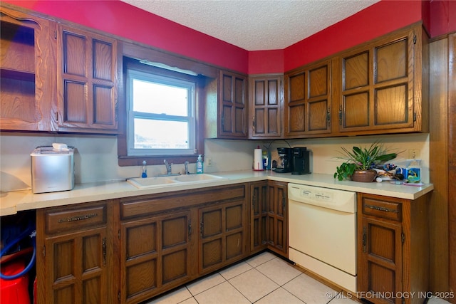 kitchen with white dishwasher, a textured ceiling, a sink, and light countertops