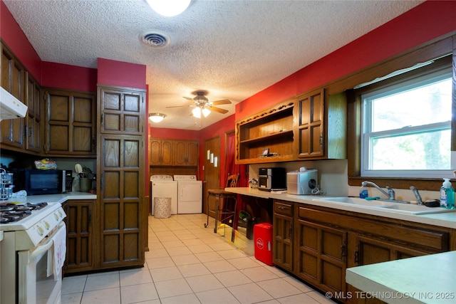 kitchen with washing machine and clothes dryer, open shelves, a sink, light countertops, and white range with gas cooktop