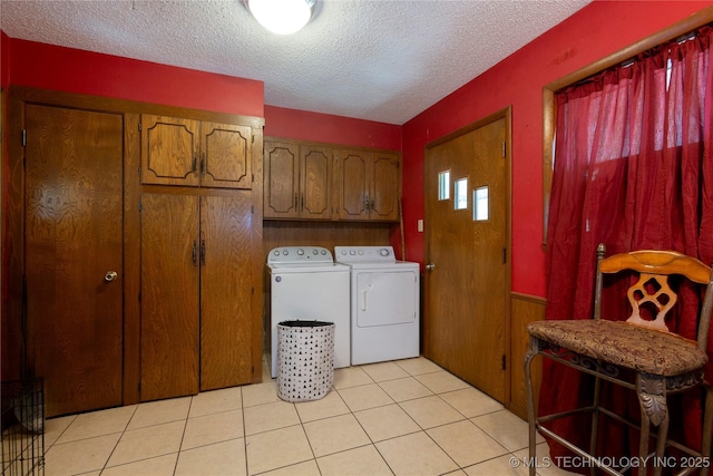 clothes washing area featuring a textured ceiling, cabinet space, independent washer and dryer, and light tile patterned flooring