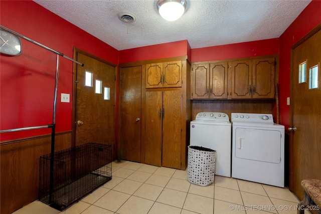 laundry room with a textured ceiling, cabinet space, light tile patterned floors, and washing machine and clothes dryer