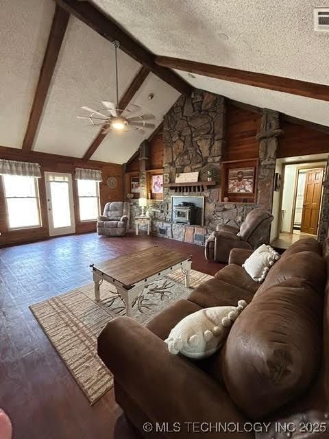 living area featuring wood finished floors, a fireplace, ceiling fan, a textured ceiling, and lofted ceiling with beams