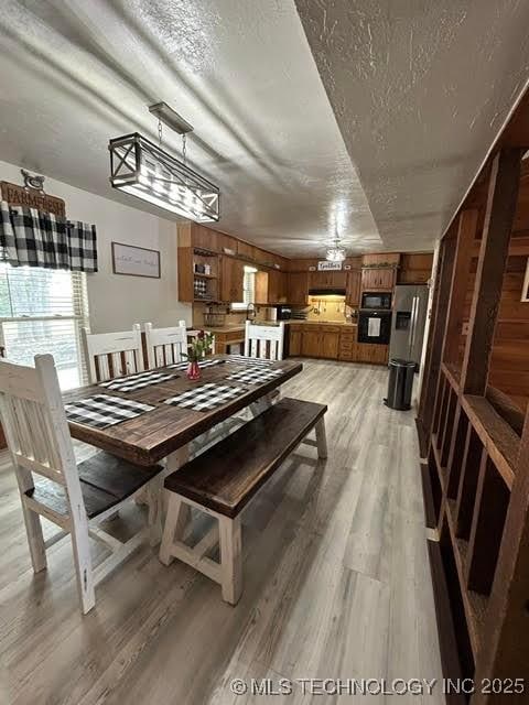 dining space featuring a textured ceiling and light wood-style floors