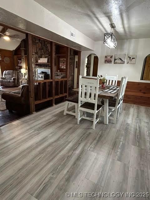 dining area with arched walkways, visible vents, and wood finished floors